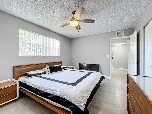bedroom featuring a textured ceiling, wood finished floors, a ceiling fan, and baseboards