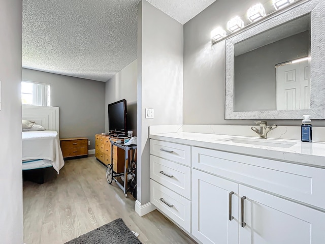 ensuite bathroom with wood finished floors, a textured ceiling, and vanity