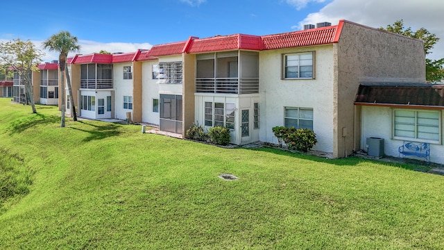 rear view of property with stucco siding, a yard, and central air condition unit