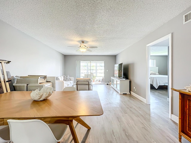 dining area with a textured ceiling, light wood-type flooring, a ceiling fan, and baseboards
