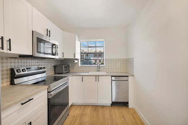 320 Norwood Ter Unit N114, Boca Raton, FL 33431 - kitchen featuring appliances with stainless steel finishes, a sink, light wood finished floors, light countertops, and backsplash