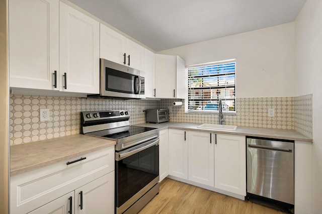 320 Norwood Ter Unit N114, Boca Raton, FL 33431 - kitchen with appliances with stainless steel finishes, a sink, light countertops, light wood-type flooring, and white cabinetry