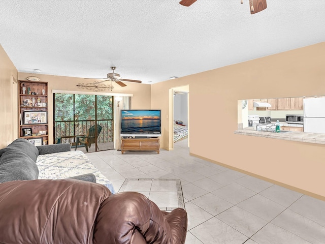 living room with a ceiling fan, a textured ceiling, baseboards, and light tile patterned floors