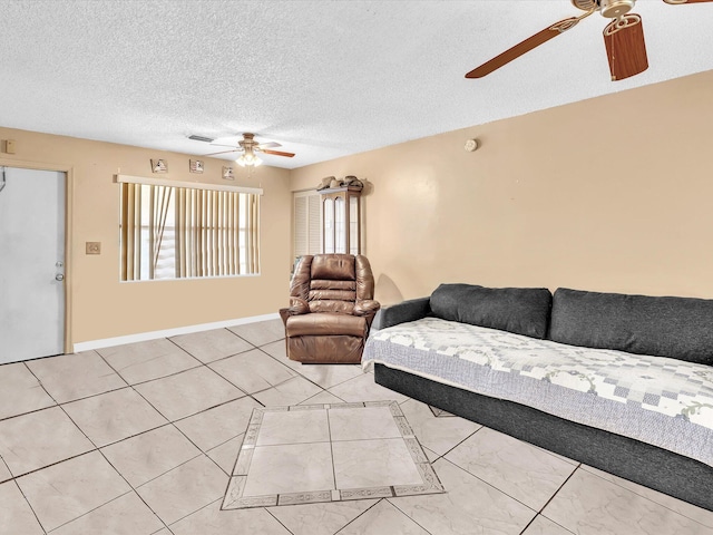 living room with a ceiling fan, a textured ceiling, baseboards, and light tile patterned floors