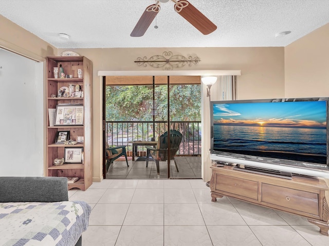 living area with a textured ceiling, ceiling fan, and light tile patterned floors