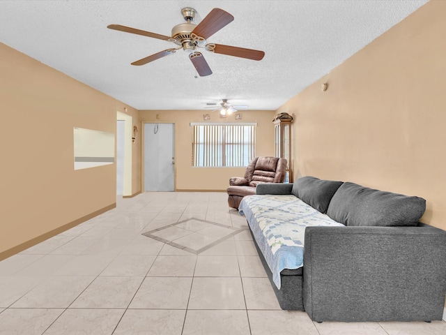living room with a textured ceiling, ceiling fan, light tile patterned flooring, and baseboards