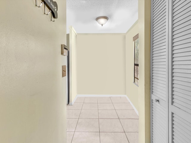 corridor with light tile patterned flooring and baseboards