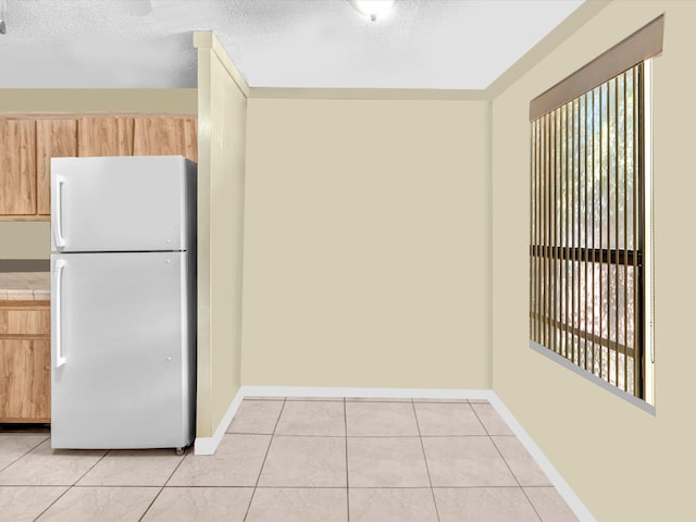 kitchen with freestanding refrigerator, light tile patterned floors, tile countertops, baseboards, and a textured ceiling