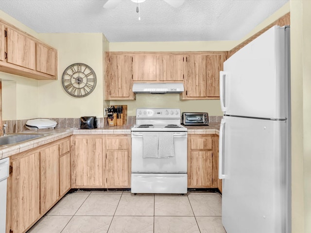 kitchen featuring white appliances, under cabinet range hood, tile counters, light brown cabinets, and ceiling fan