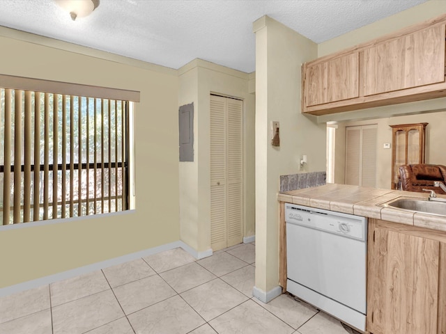 kitchen featuring white dishwasher, light brown cabinets, a sink, baseboards, and a textured ceiling