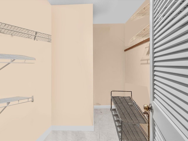 spacious closet featuring light marble finish floors