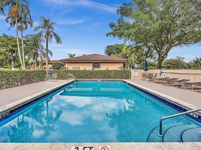 community pool with a patio area and fence