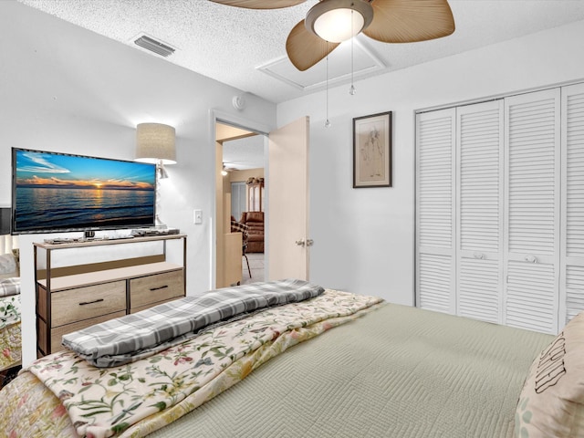 bedroom with attic access, a closet, ceiling fan, and a textured ceiling
