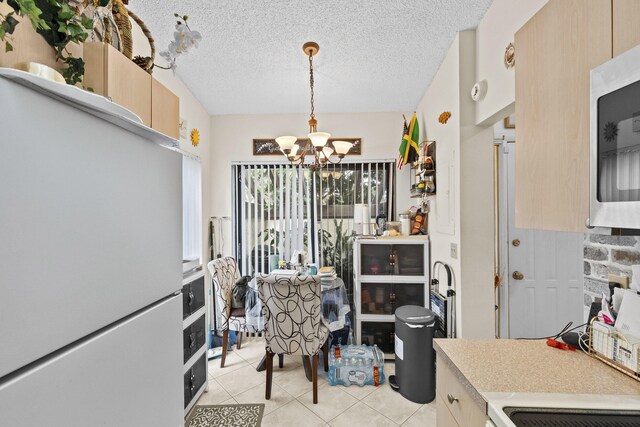 3646 English D Rd Unit D, Lake Worth, FL 33467 - kitchen with a chandelier, light tile patterned flooring, stainless steel microwave, freestanding refrigerator, and light countertops
