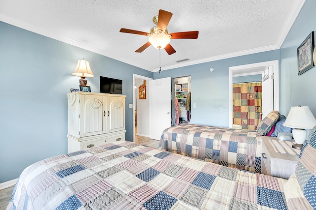 bedroom with light wood finished floors, a textured ceiling, ceiling fan, ornamental molding, and baseboards