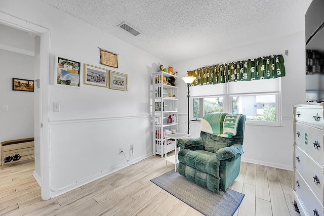 sitting room featuring wood finished floors, a textured ceiling, and baseboards