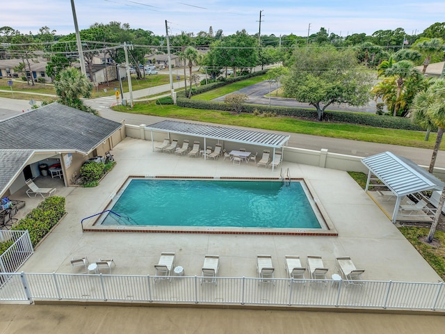 community pool with a patio area and fence