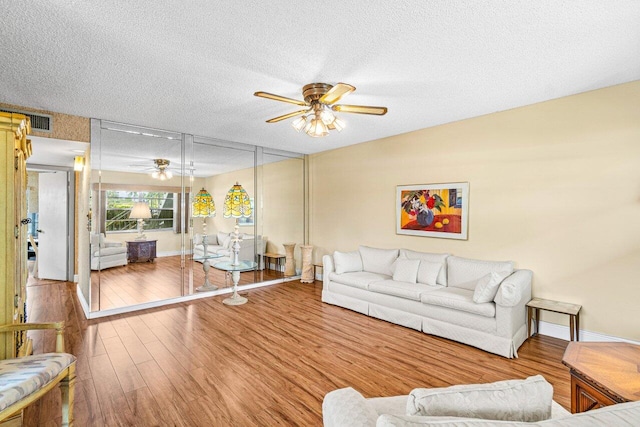 living room featuring a ceiling fan, wood finished floors, a textured ceiling, and baseboards