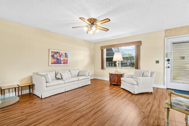 living area featuring wood finished floors, a ceiling fan, a textured ceiling, and baseboards