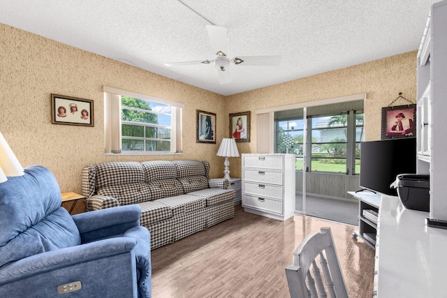 living room with wood finished floors, ceiling fan, and a textured ceiling