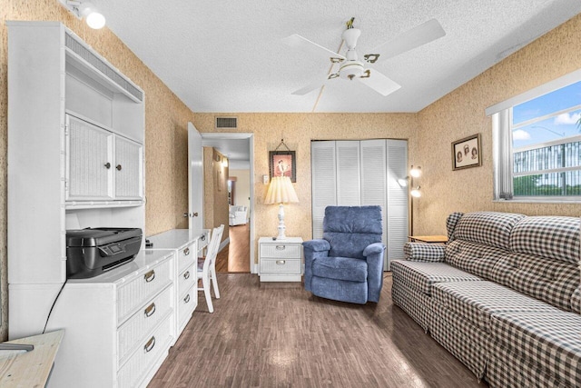 living area featuring dark wood-style floors, ceiling fan, and a textured ceiling