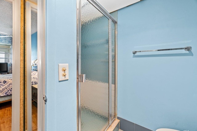full bathroom featuring connected bathroom, a shower stall, and wood finished floors