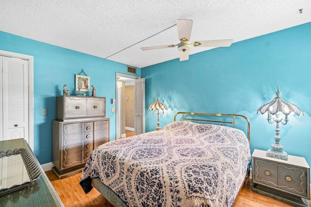 bedroom featuring wood finished floors, a textured ceiling, a ceiling fan, a closet, and baseboards