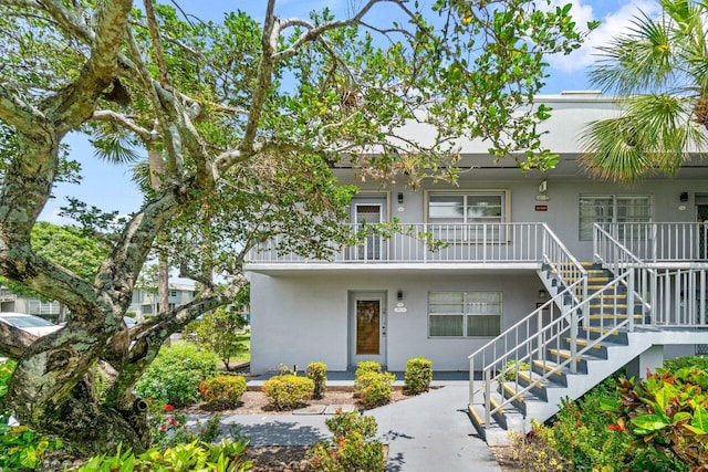 view of front facade featuring a porch, stucco siding, and stairs