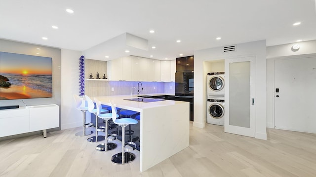 5100 Dupont Blvd Unit 7E, Fort Lauderdale, FL 33308 - kitchen featuring modern cabinets, stacked washing machine and dryer, a breakfast bar, a peninsula, and tasteful backsplash