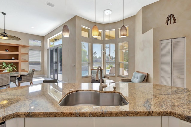 19236 Bay Leaf Ct, Boca Raton, FL 33498 - kitchen with a sink, light stone counters, open floor plan, white cabinets, and pendant lighting