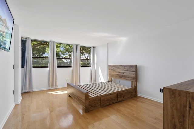 bedroom with light wood-style flooring, multiple windows, and baseboards