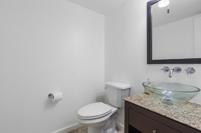 bathroom with baseboards, toilet, and vanity