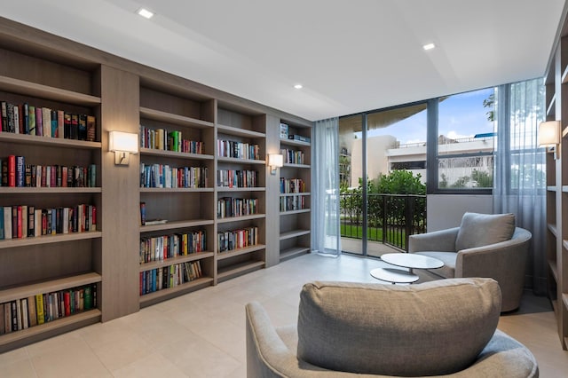 sitting room with bookshelves, tile patterned floors, expansive windows, and built in shelves
