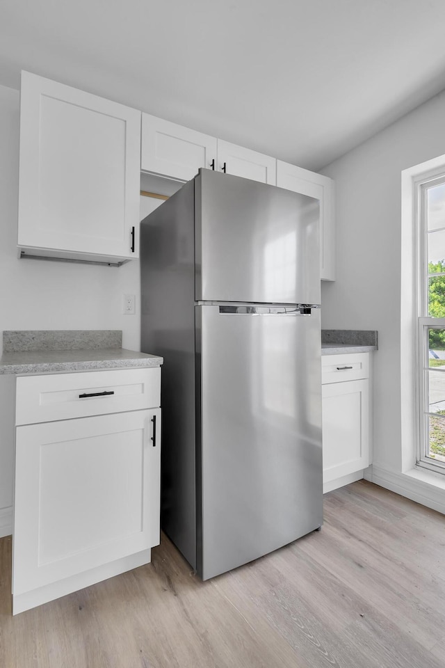 907 Skylark Dr, Fort Pierce, FL 34982 - kitchen featuring freestanding refrigerator, light wood-style floors, white cabinetry, and light countertops
