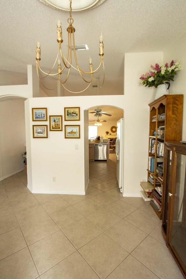 dining area featuring arched walkways, light tile patterned floors, a textured ceiling, a chandelier, and baseboards