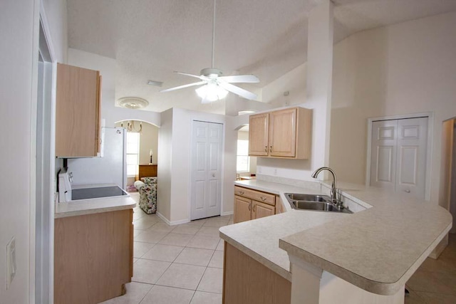 kitchen with a sink, light brown cabinetry, arched walkways, ceiling fan, and a peninsula