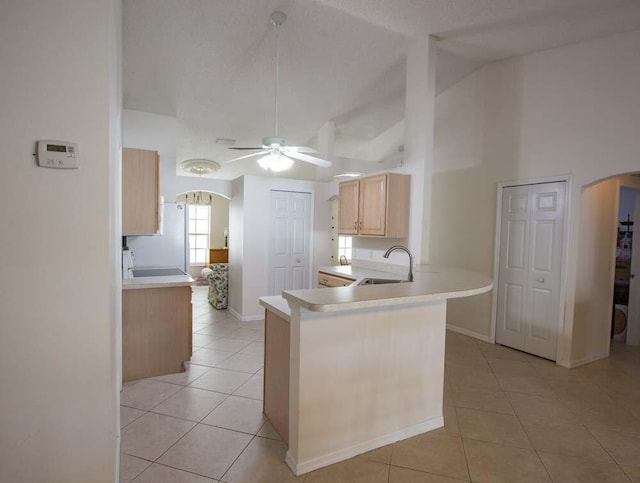 kitchen featuring a sink, arched walkways, light tile patterned floors, a ceiling fan, and light brown cabinetry