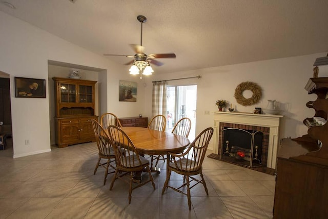 dining space featuring tile patterned flooring, ceiling fan, and a fireplace