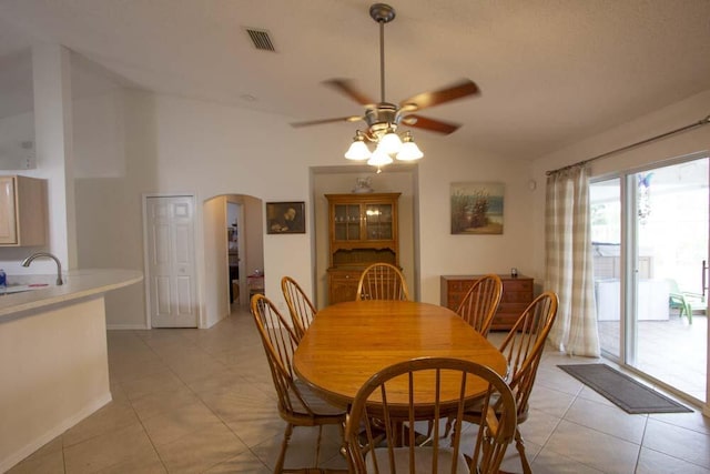 dining space featuring arched walkways, vaulted ceiling, a ceiling fan, and light tile patterned floors