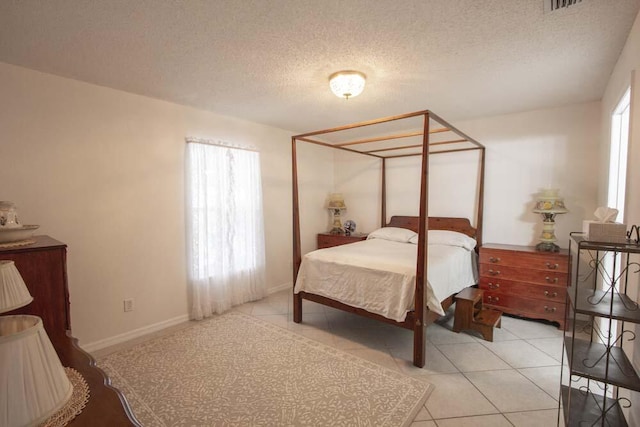 bedroom with a textured ceiling, tile patterned floors, and baseboards