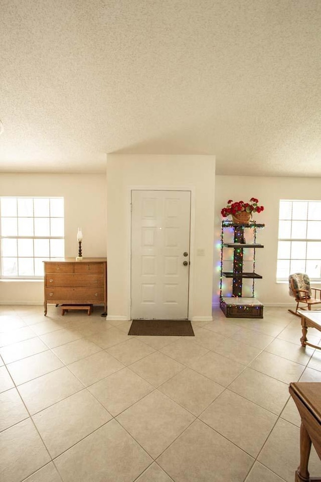 entrance foyer with light tile patterned flooring, a textured ceiling, and baseboards