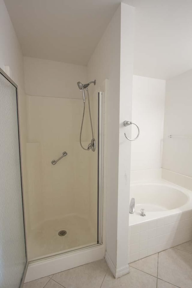 bathroom with tile patterned floors, a stall shower, a garden tub, and baseboards