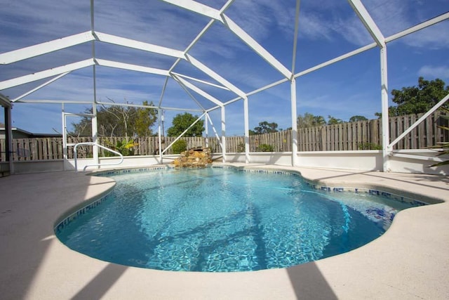 view of swimming pool featuring a patio, a fenced backyard, and glass enclosure
