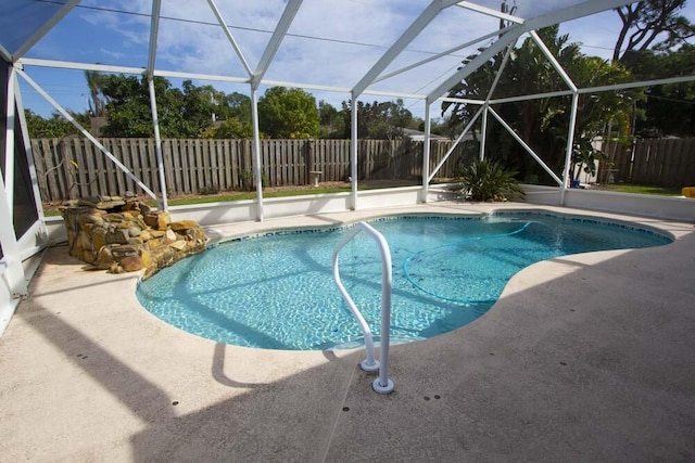 view of swimming pool featuring a fenced backyard, a patio area, and glass enclosure