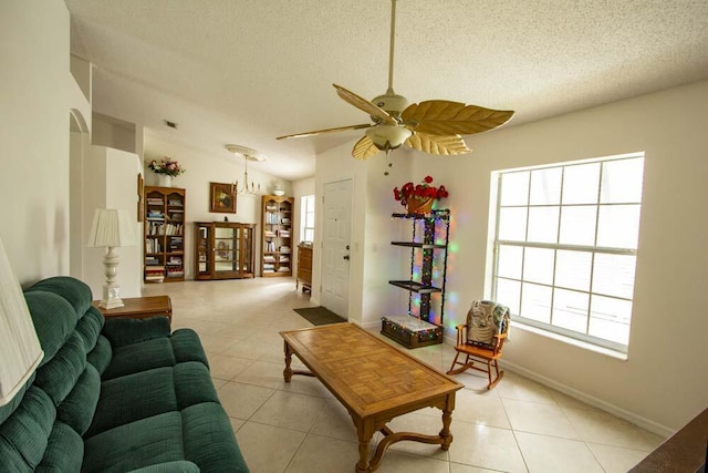 living area with a textured ceiling, light tile patterned floors, a ceiling fan, baseboards, and lofted ceiling