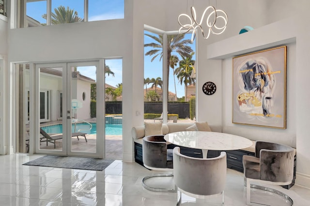 dining room with a high ceiling, a chandelier, and marble finish flooring