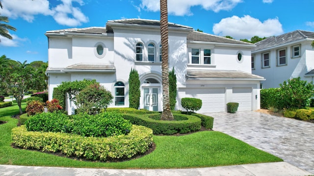 view of front facade with an attached garage, stucco siding, decorative driveway, and a tile roof