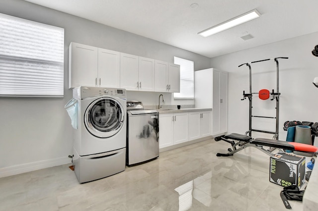laundry room featuring cabinet space, washing machine and dryer, light tile patterned floors, and baseboards