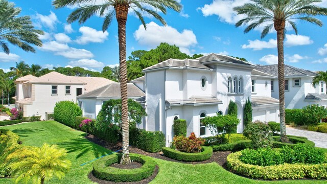 view of front of property featuring stucco siding, a front lawn, and a garage