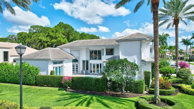 back of property with french doors, a lawn, stucco siding, and a tiled roof